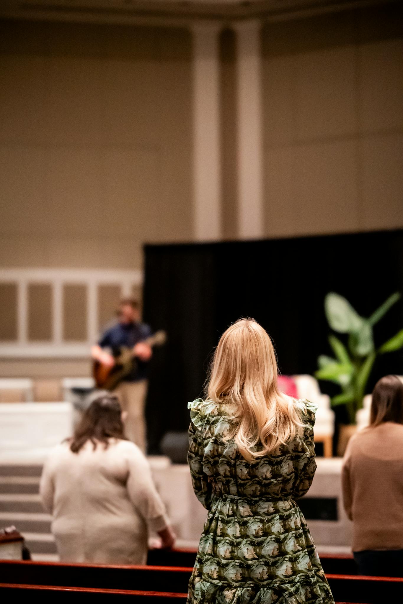 A church service with people worshiping and a musician on stage.