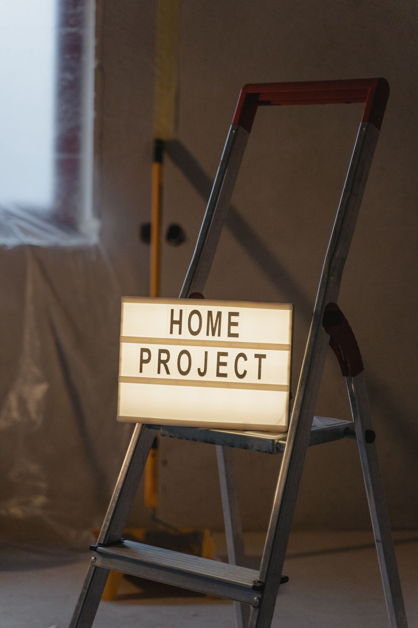A lit sign on a ladder indicating a home renovation project.